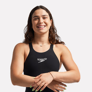 Female swimmer in black suit smiling with arms crossed