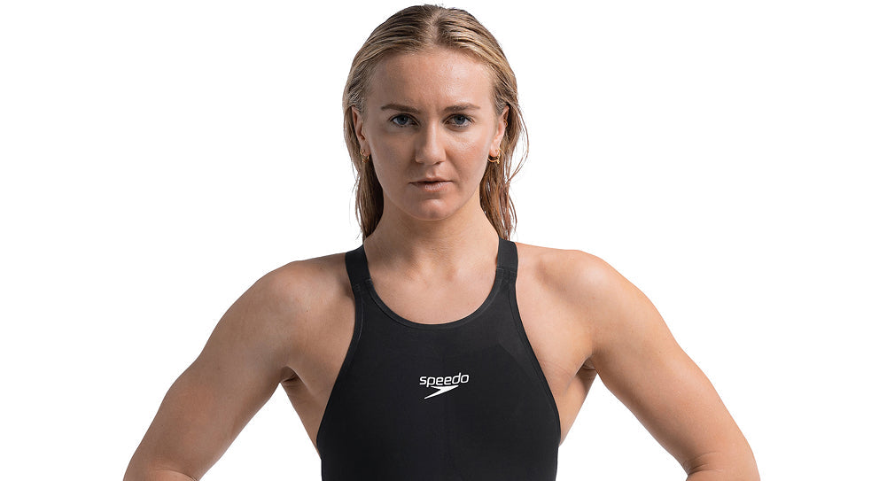 Swimmer in a black suit facing forward against a plain background.